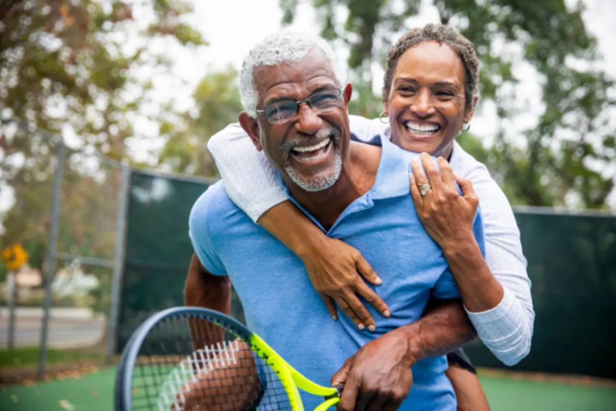 benefits of exercise at any age senior black couple on tennis court piggyback